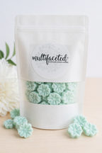 White packaging of mint green floral candies with 'multifaceted' label on a light background.