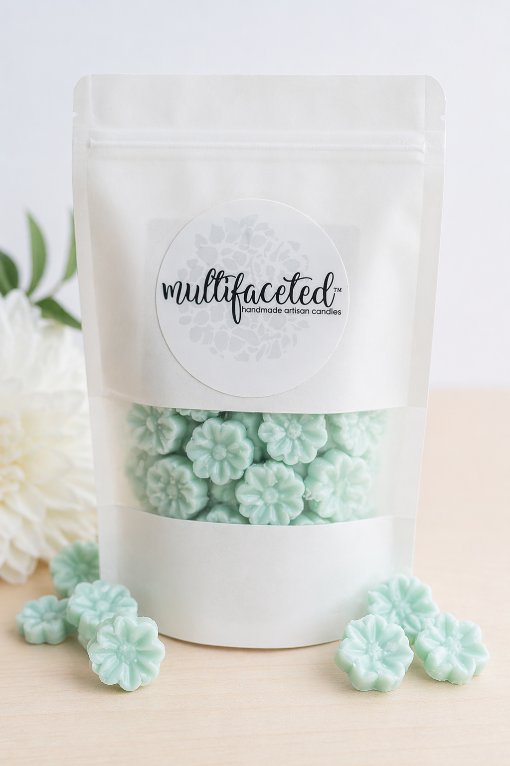 White packaging of mint green floral candies with 'multifaceted' label on a light background.