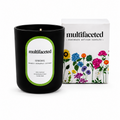 Black candle with green label and floral packaging on a white background