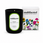 Black candle with green label and floral packaging on a white background