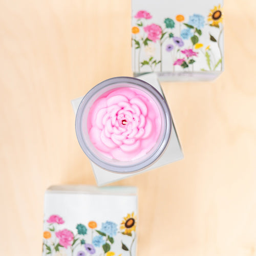 Candle with floral packaging on a beige background